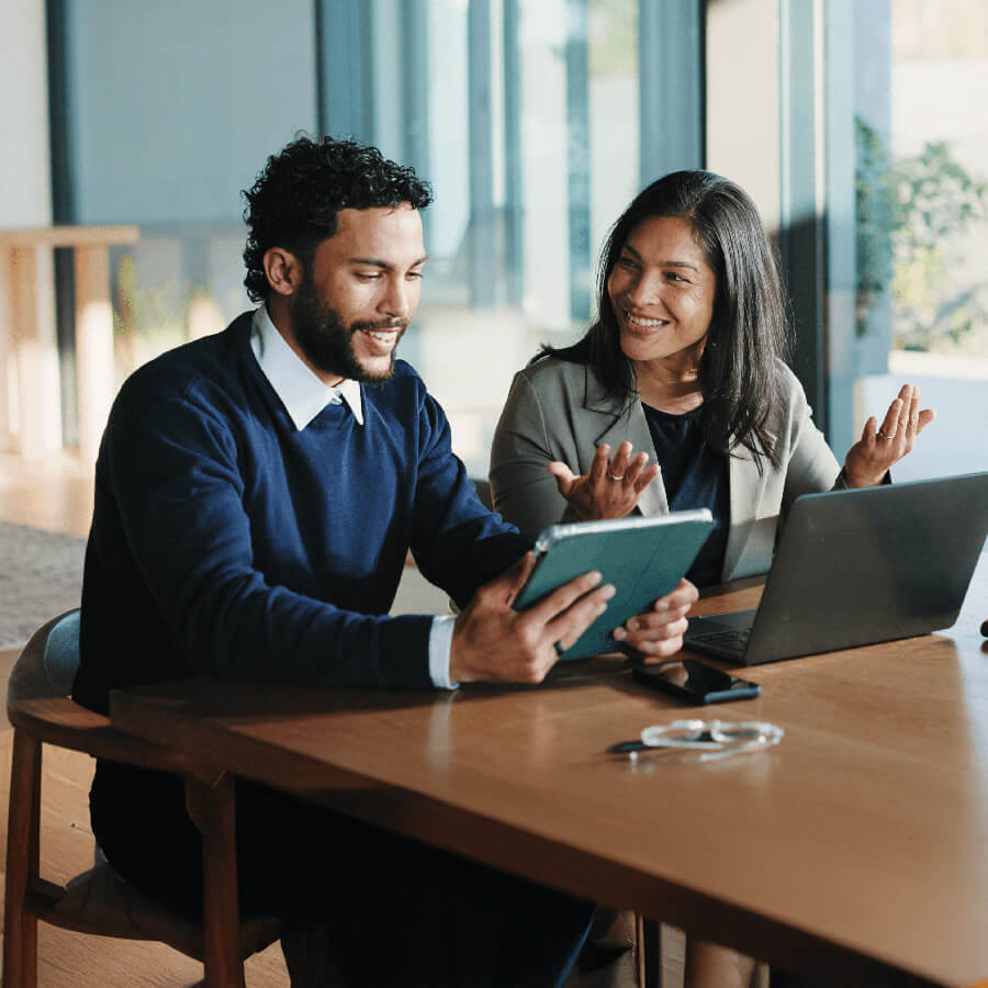man and woman looking at tablet and computer discussing